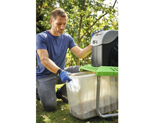 Muž vyprazdňuje nádobu zahradního drtiče na zahradě.