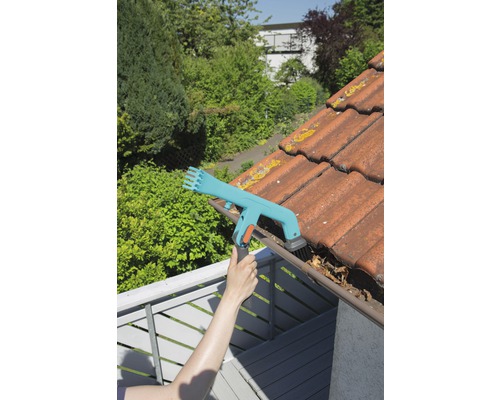 Osoba čistí okap čističem okapů