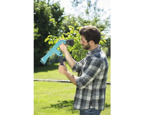 Muž v zahradě používá sběrač ovoce ke sklizni.