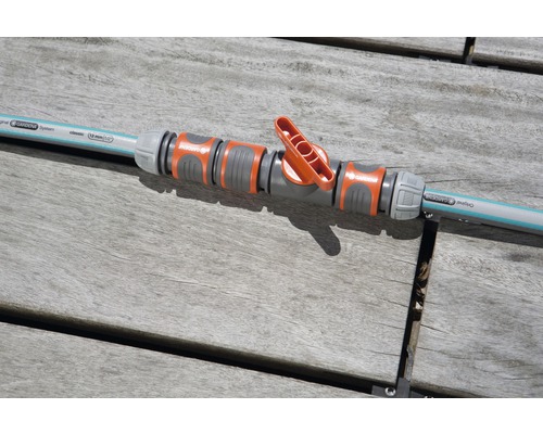 Regulační ventil Gardena spojený se zahradní hadicí na dřevěném stole