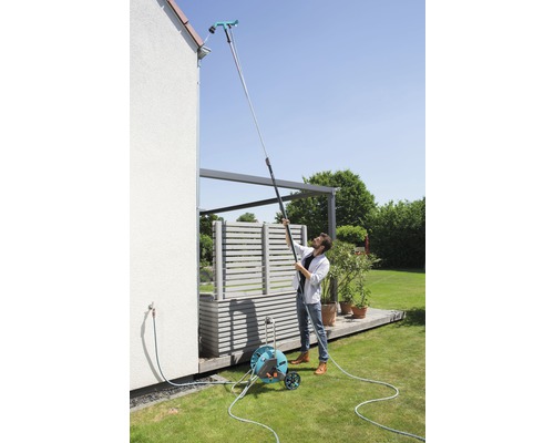 Muž čistí okap čističem okapů na teleskopické tyči