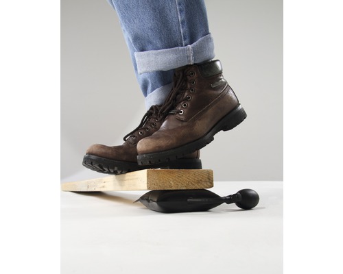 Osoba v botách balancuje na vzduchovém polštáři mezi kusy dřeva