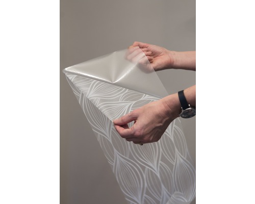 Role tapety se vzorem drží dvě ruce.