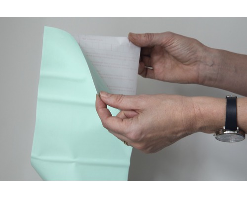 Osoba odstraňuje ochrannou fólii z fólie.