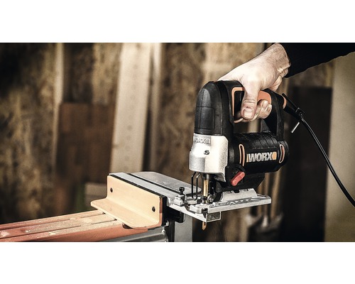 Ruka drží přímočarou pilu při řezání dřeva