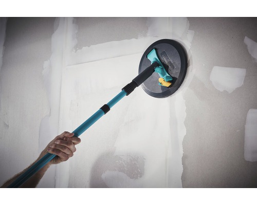 Osoba používá brusku na strop s teleskopickou tyčí na stěně.