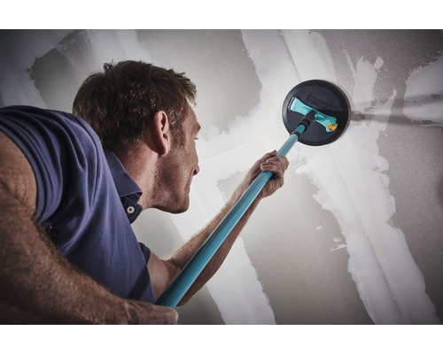 Muž brousí stěnu pomocí brusky na sádrokarton pro renovaci