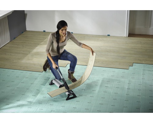 Žena řeže laminát řezačkou laminátu na podložce