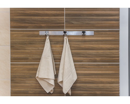 Pohled na koupelnu s ručníky na držáku ručníků před stěnou s dřevěnými obklady