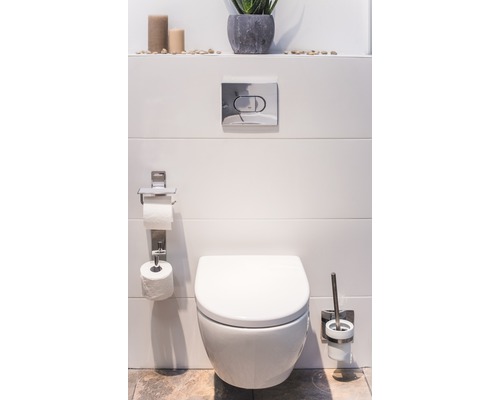 Moderní koupelna se závěsným WC, držákem toaletního papíru a sadou štětek na WC.