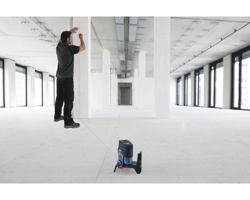 Muž pracuje s čárovým laserem v hrubé stavbě pro vyrovnání.