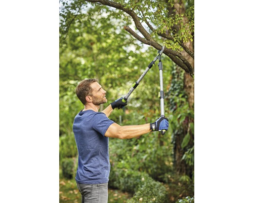 Muž stříhá větev nůžkami na větve na zahradě.