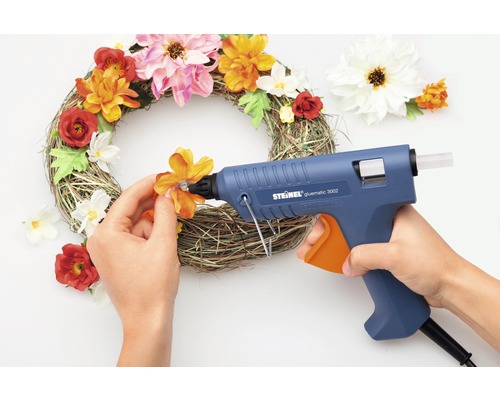 Dekorativní věnec je zdoben tavnou lepicí pistolí a umělými květinami.