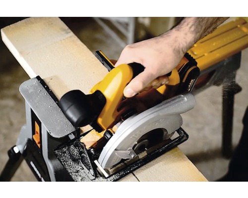 Ruční kotoučová pila řeže dřevěnou desku na kozlíku