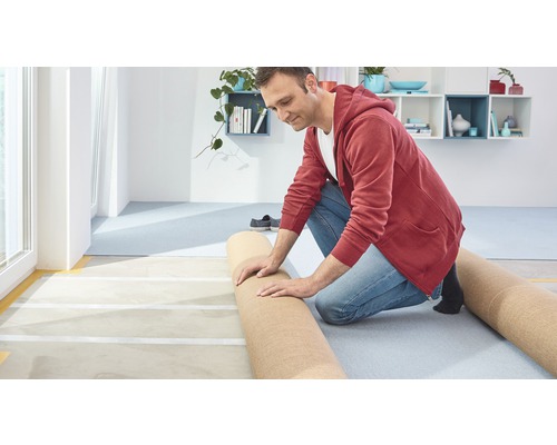 Muž pokládá koberec v místnosti.