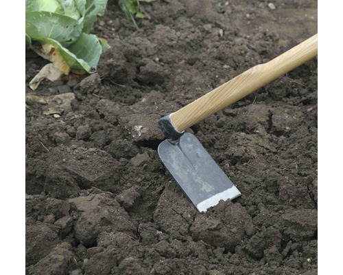 Motyka s dřevěnou násadou v zahradní půdě