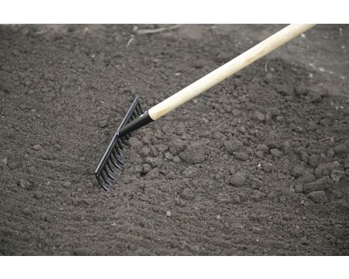 Zahradní hrábě s dřevěnou násadou používané na zemi