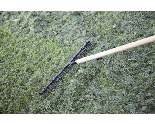 Kovové hrábě s dřevěnou násadou na trávníku