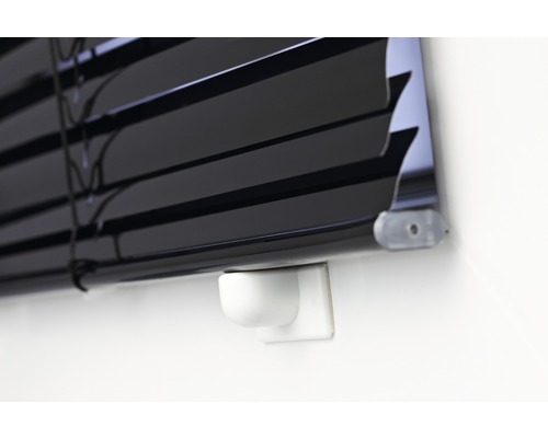 Detailní pohled na černé žaluzie na zdi.