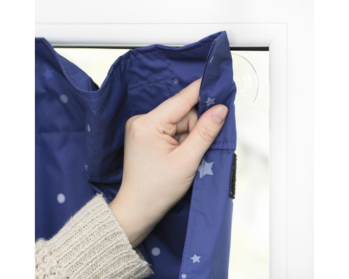 Detail zatemňovací rolety se vzorem hvězd, připevněné přísavkou k oknu.