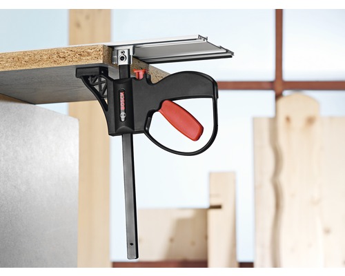 Logo Bosch. Obrobek připevněný k vodicí liště pomocí jednoruční svorky Bosch.