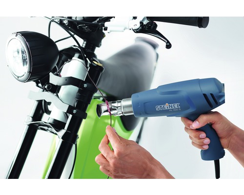 Osoba používá horkovzdušnou pistoli Steinel HL 1620 S na motocyklu.