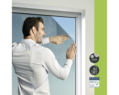 Muž instaluje protipylovou fólii na okno. Viditelné jsou také symboly ochrana proti pylu, lze prát na 30 stupňů a vhodné pro alergiky.