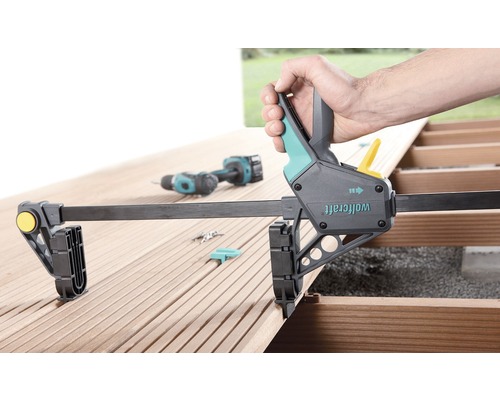 Jednoruční svěrka Wolfcraft na dřevěné terase při použití s akumulátorovým šroubovákem