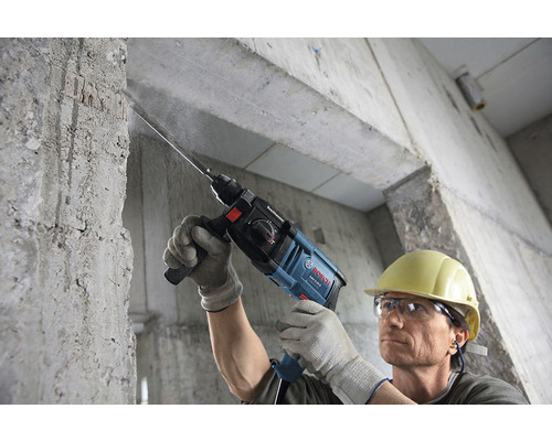 Muž vrtá do betonové zdi pomocí vrtacího kladiva Bosch