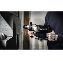 Osoba vrtá aku vrtacím kladivem do cihlové zdi. Je vidět logo Worx.