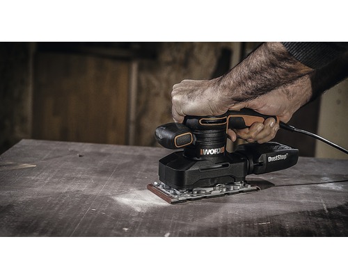 Osoba používá excentrickou brusku WORX na dřevěném povrchu.