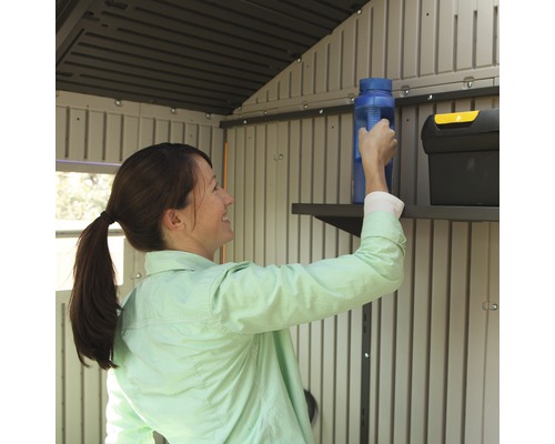 Žena uklízí náčiní na polici v zahradním domku