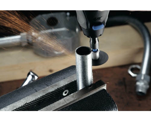 Potrubní svěrák drží trubku, zatímco ji multifunkční nástroj opracovává a odletují z ní jiskry.