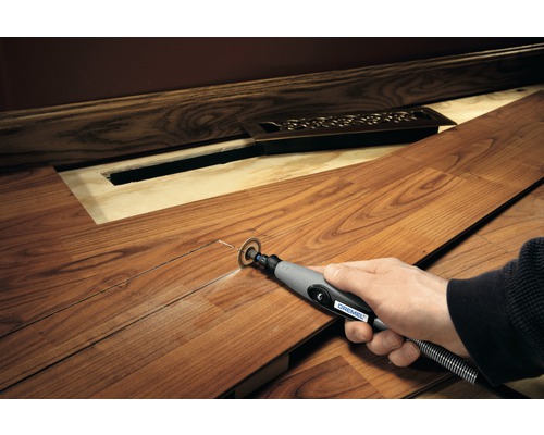 Osoba řeže laminátovou desku multifunkčním nástrojem Dremel, aby vytvořila prostor pro radiátor.