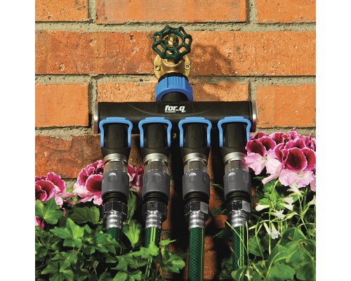 Rozdělovač for.q se čtyřmi přípojkami a připojenými zahradními hadicemi před cihlovou zdí