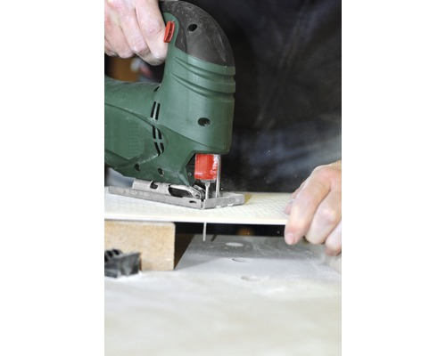 Přímočará pila řeže obrobek na pracovním stole.