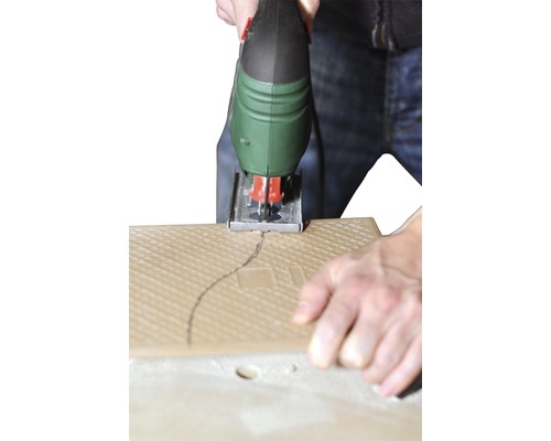 Přímočará pila řeže dlaždici podél nakreslené čáry.