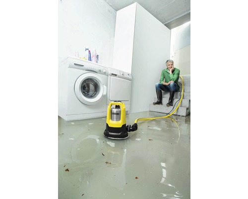 Scéna s ponorným čerpadlem v zatopené místnosti vedle pračky a sušičky. Osoba sedí uvolněně na schodech.