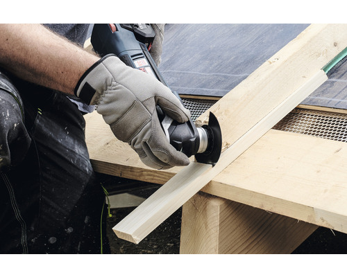 Osoba řeže dřevěnou desku multifunkčním nástrojem.