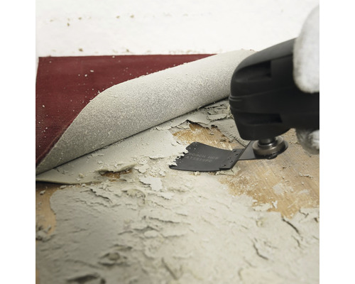 Oscilační multifunkční nástroj odstraňuje zbytky lepidla z dřevěné podlahy