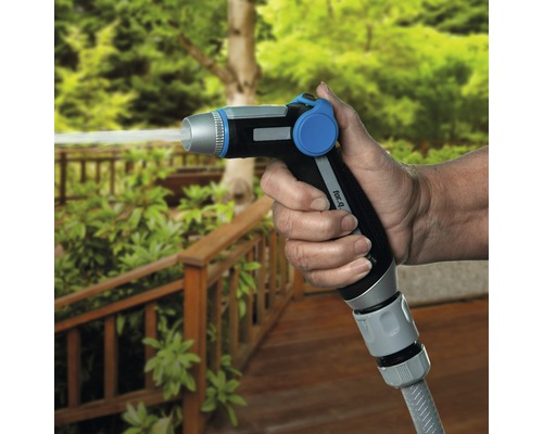 Osoba drží zahradní rozprašovací hlavici, ze které vychází voda.