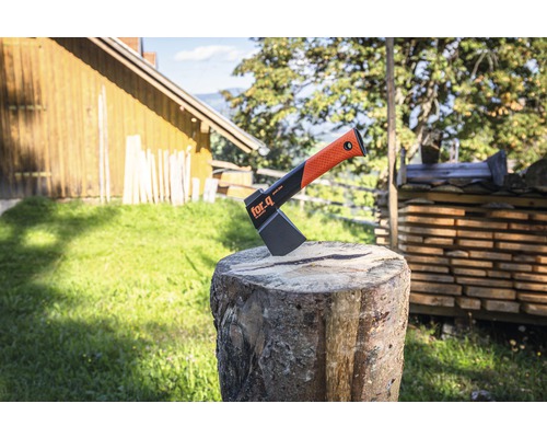 Štípací sekera For_q na špalku před hromadou dřeva a krajinou