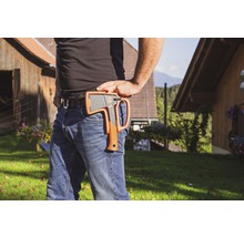 Osoba se sekerou v pouzdře na opasku ve venkovním prostředí.