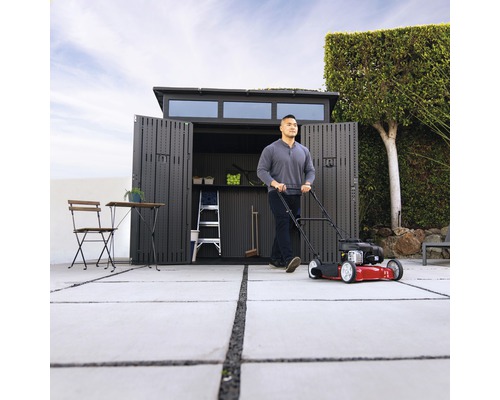 Scéna s sekačkou na trávu před otevřeným zahradním domkem, žebříkem a zahradním nábytkem