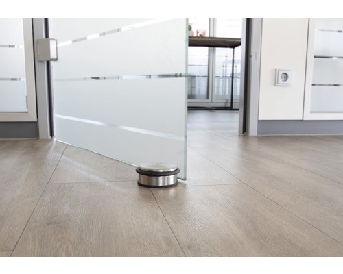 Nerezová zarážka dveří na dřevěné podlaze před skleněnými dveřmi