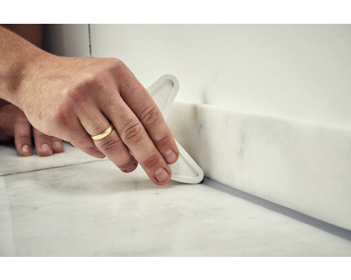 Nanášení těsnicí hmoty spárovacím nástrojem.