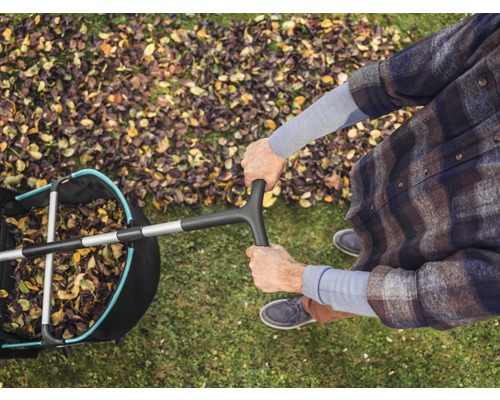 Pohled shora na osobu s lapačem listí na trávníku s podzimním listím