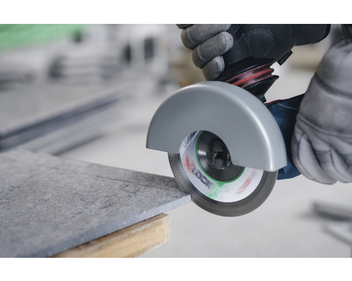 Osoba řeže dlaždici úhlovou bruskou