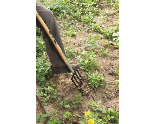 Osoba používá rycí vidle k práci na zahradě.