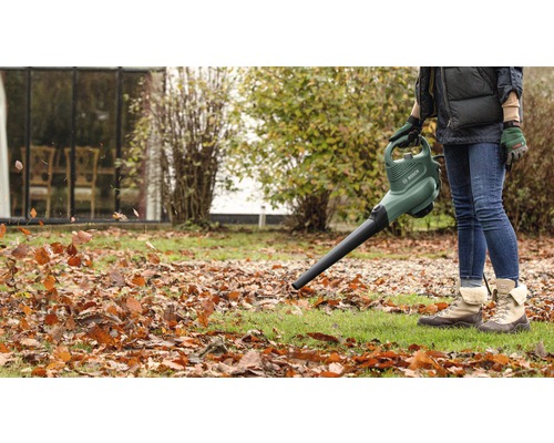 Osoba používá fukar na listí na zahradě k odstranění listí.